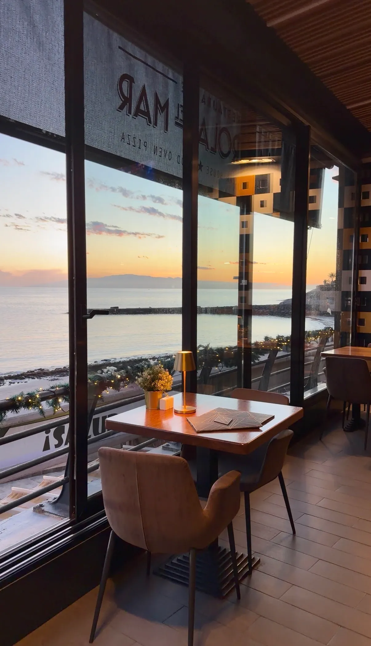 Mesa junto al ventanal con vista al mar al atardecer